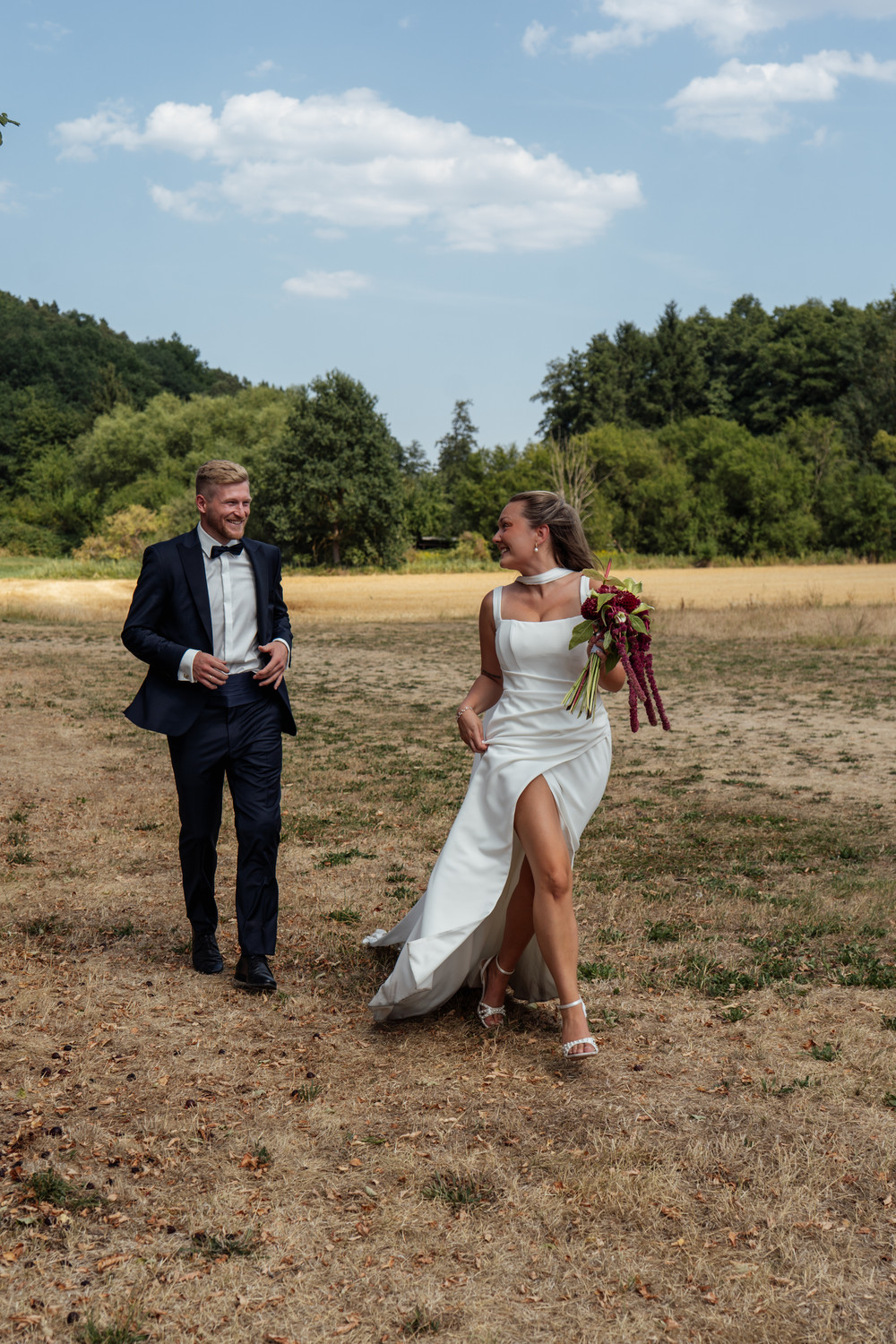 Brautpaar lacht auf einer Wiese